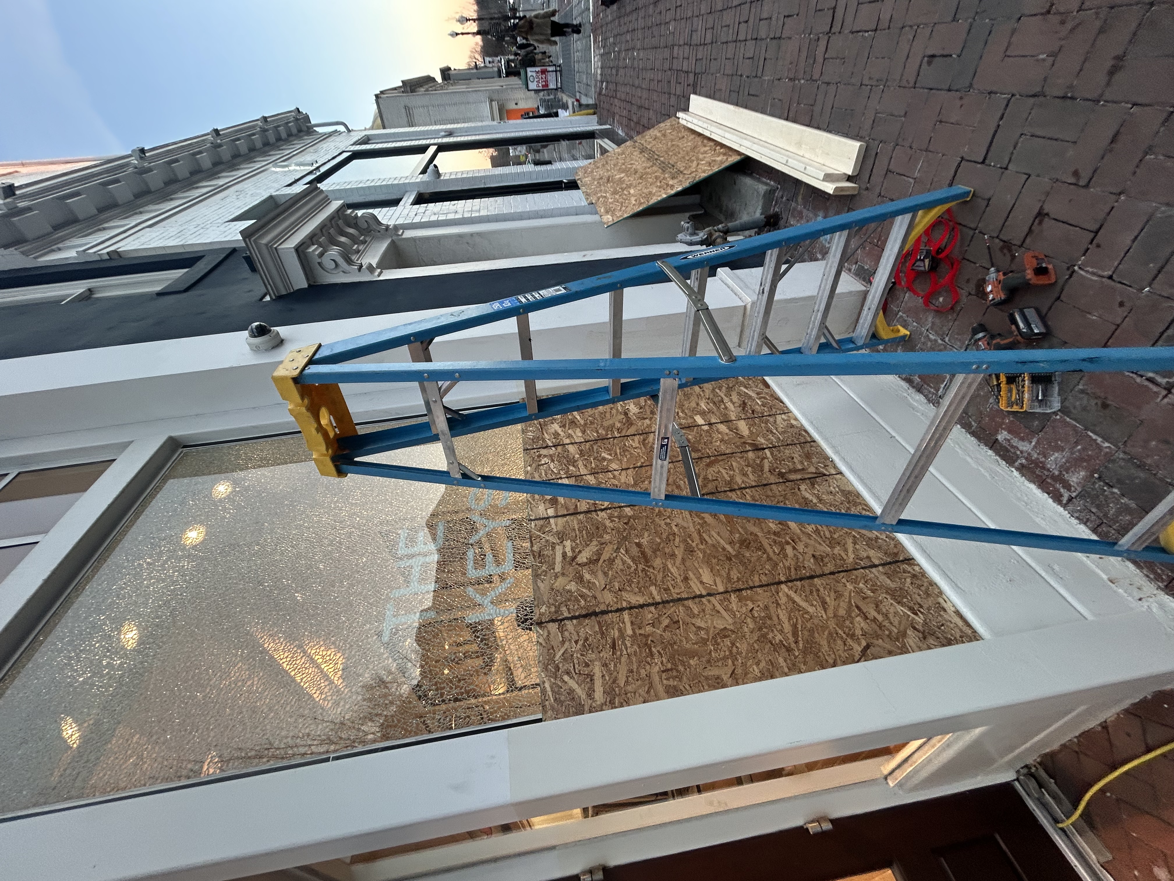 Emergency board-up service on a damaged commercial storefront
